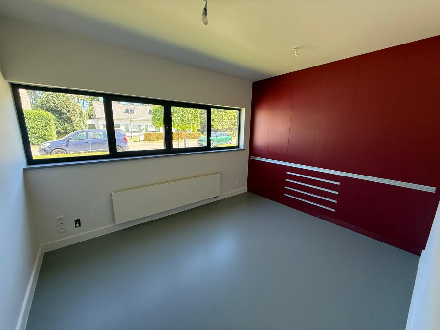 Slaapkamer met rode maatkastenwand en gietvloer