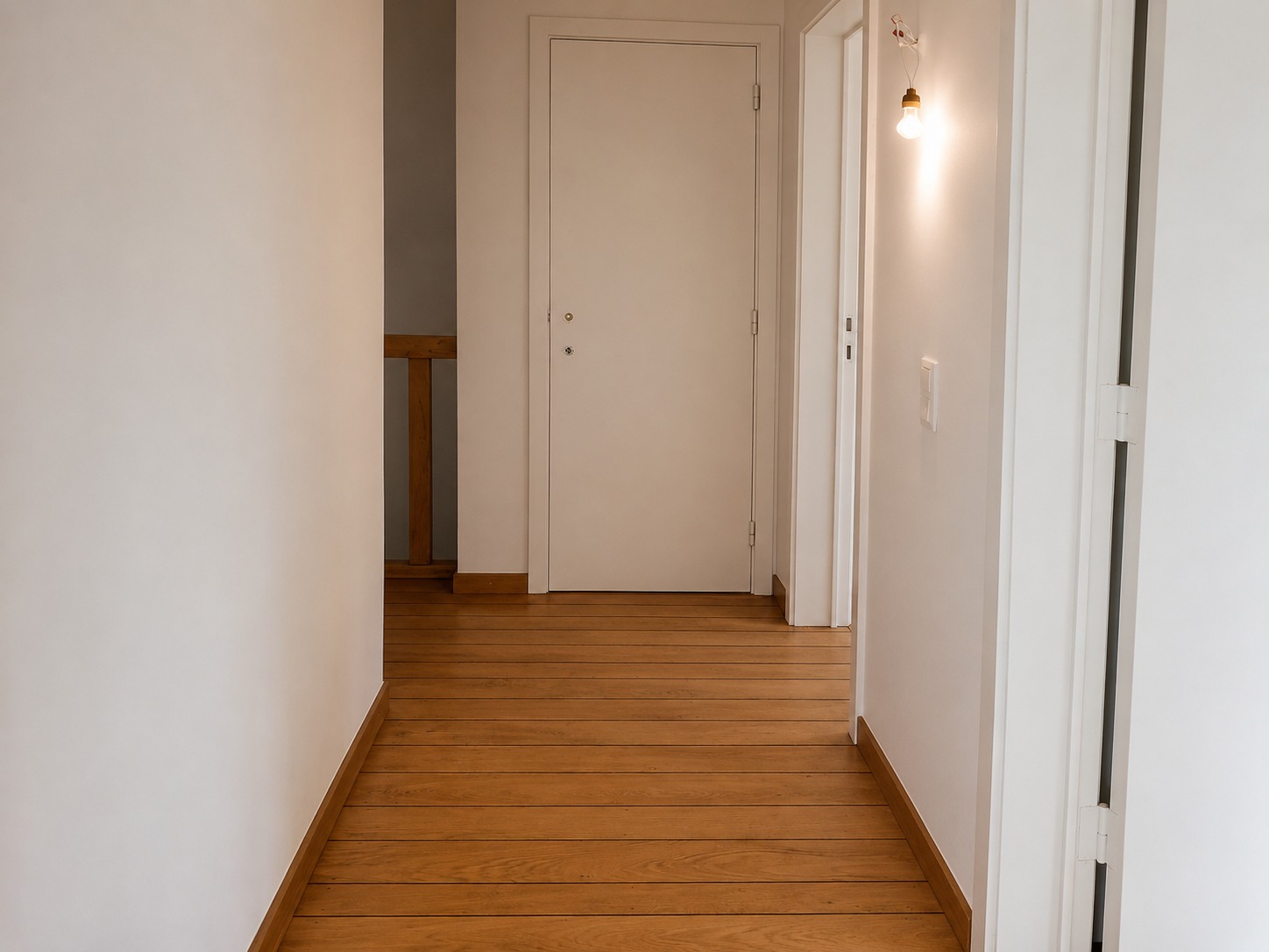 Gang met nieuwe houten vloer en strak geschilderde wanden en deuren