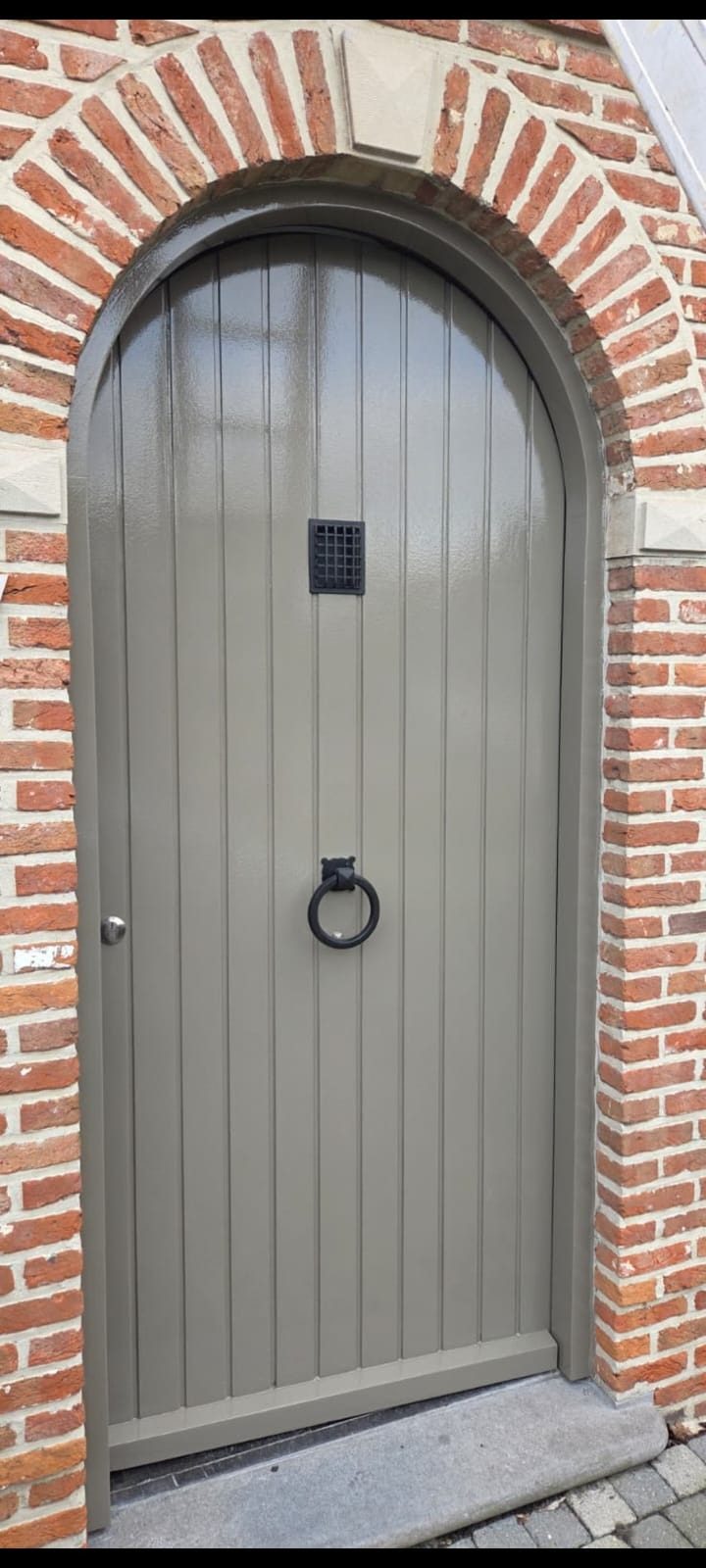 Gerenoveerde en geschilderde boogdeur in bakstenen gevel